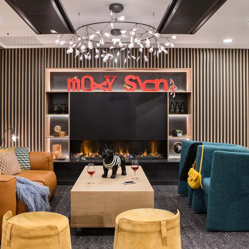 salon avec feu de cheminée canapés fauteuils confortables design à l'hôtel Moxy de Sion de l'